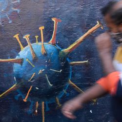 Un peatón levanta su mascarilla mientras pasa por delante de un mural en el que se insta a los ciudadanos a utilizar correctamente las mascarillas para concienciar sobre el coronavirus Covid-19 en Bombay, India. | Foto:INDRANIL MUKHERJEE / AFP