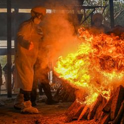 Voluntarios con trajes de equipo de protección personal (EPP) y un familiar realizan los últimos ritos durante la cremación de una persona fallecida a causa del coronavirus Covid-19, en un campo de cremación en Nueva Delhi, India. | Foto:PRAKASH SINGH / AFP