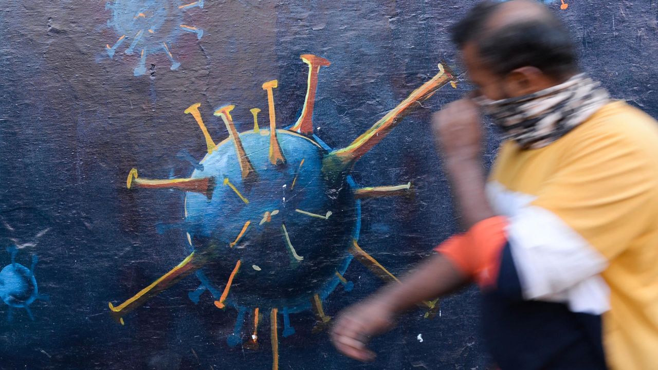 Un peatón levanta su mascarilla mientras pasa por delante de un mural en el que se insta a los ciudadanos a utilizar correctamente las mascarillas para concienciar sobre el coronavirus Covid-19 en Bombay, India. | Foto:INDRANIL MUKHERJEE / AFP