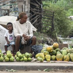 Una vendedora ambulante, flanqueada por su hijo, vende frutas en una calle de Douala, Camerún. | Foto:CHARLY TRIBALLEAU / AFP