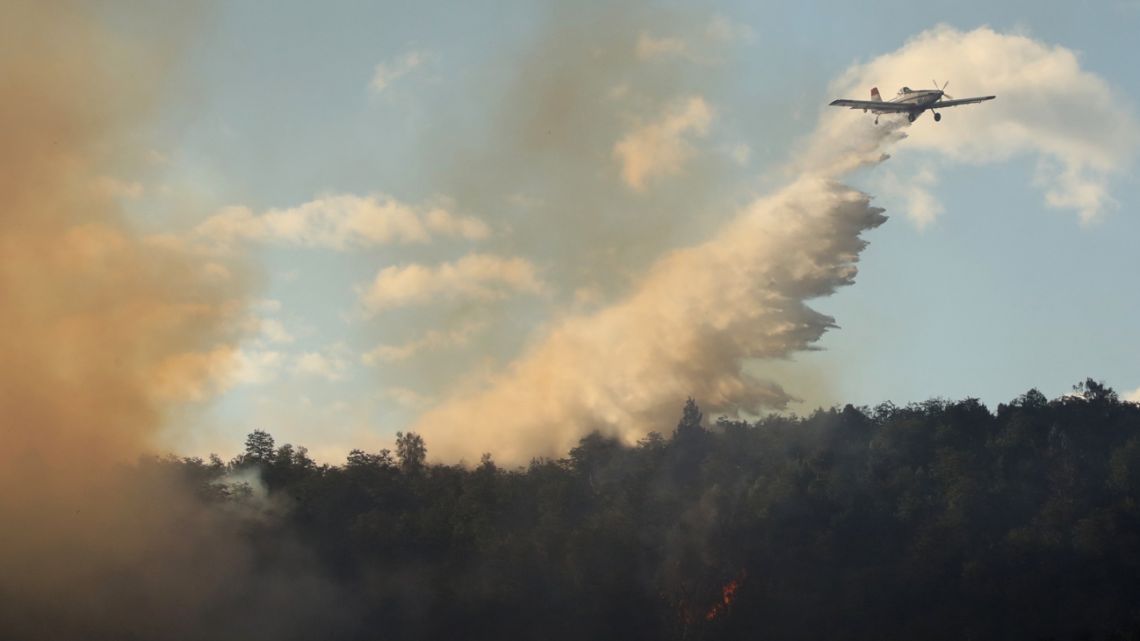 A firefighting plane dumps water over a huge forest fire near Ruta 40, some 12 km from Paraje Villegas and 60 km south of Bariloche, Rio Negro Province on January 13, 2022. Several sources of fire have been active for weeks in the provinces of Neuquén, Río Negro and Chubut (south), where the flames have consumed thousands of hectares of native forest amid adverse weather conditions.