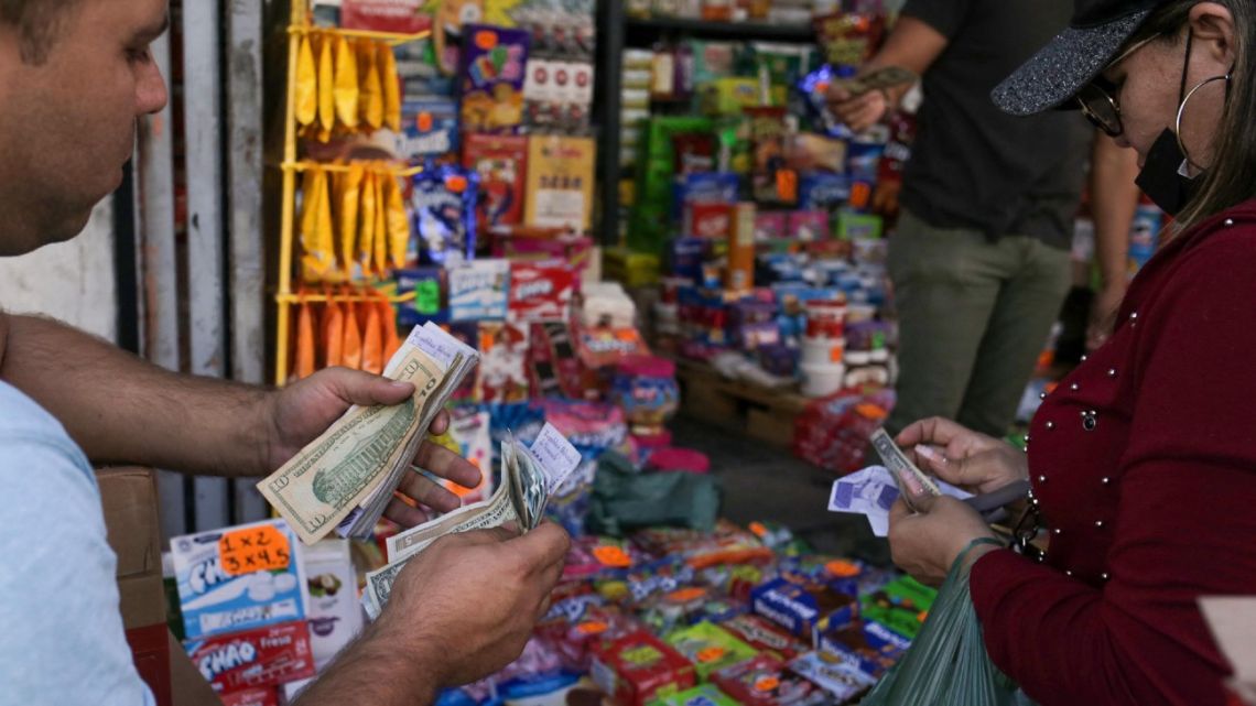 A grocery vendor counts Venezuelan bolívares and US dollar notes with a costumer, in Caracas, on January 13, 2022. 