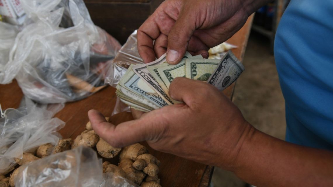 A vendor counts US dollars at a market in Caracas, Venezuela, on Monday, October 4, 2021. 