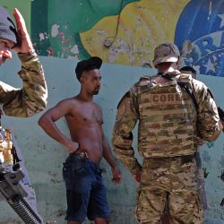 Miembros del CORE, un ala de operaciones especiales de la Policía Civil brasileña, comprueban la identidad de dos hombres durante una operación a gran escala contra el tráfico de drogas, para ocupar y asegurar partes de la favela de Jacarezinho en Río de Janeiro, Brasil. | Foto:CARL DE SOUZA / AFP