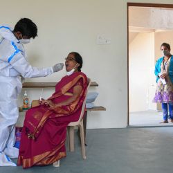 Un trabajador médico toma una muestra de hisopo de una mujer para una prueba de reacción en cadena para el coronavirus Covid-19 en una universidad en Bangalore, India. | Foto:Manjunath Kiran / AFP