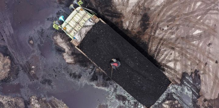 Esta imagen aérea muestra a un trabajador de pie en la parte trasera de un camión cargado de carbón en el puerto de Karya Citra Nusantara en Yakarta, después de que Indonesia aliviara la prohibición de exportar este producto.