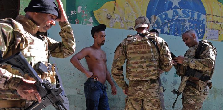 Miembros del CORE, un ala de operaciones especiales de la Policía Civil brasileña, comprueban la identidad de dos hombres durante una operación a gran escala contra el tráfico de drogas, para ocupar y asegurar partes de la favela de Jacarezinho en Río de Janeiro, Brasil.