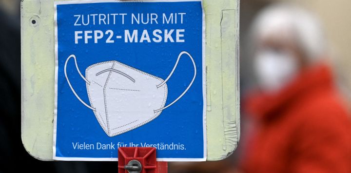 Un cartel informa a la gente de que debe cubrirse la boca y la nariz con una mascarilla frente a un centro de pruebas de la pandemia de Covid-19 en el pequeño pueblo de Unterschleissheim, cerca de Múnich, en el sur de Alemania, en medio de la actual pandemia de coronavirus Covid-19.