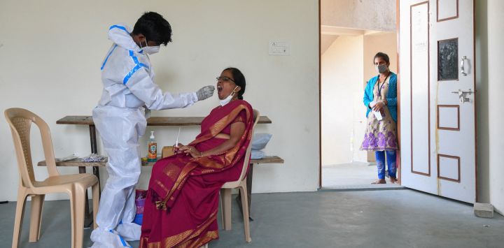 Un trabajador médico toma una muestra de hisopo de una mujer para una prueba de reacción en cadena para el coronavirus Covid-19 en una universidad en Bangalore, India.
