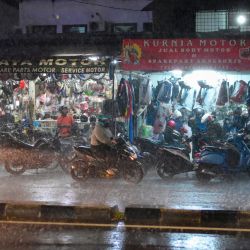Motociclistas se detienen frente a tiendas de carretera para resguardarse de la lluvia durante un fuerte aguacero en Yakarta, Indonesia. | Foto:BAY ISMOYO / AFP
