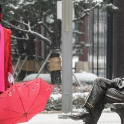 Un hombre vestido de rojo se hace una foto cerca de una estatua durante una ligera nevada en Seúl. | Foto:ANTHONY WALLACE / AFP