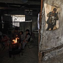 Una familia palestina se calienta junto a un fuego en un día lluvioso en Khan Yunis, en el sur de la Franja de Gaza. | Foto:MAHMUD HAMS / AFP