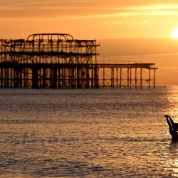 Un nadador madrugador disfruta de su baño mientras el sol sale cerca del muelle oeste en Brighton, al sur de Inglaterra. | Foto:GLYN KIRK / AFP