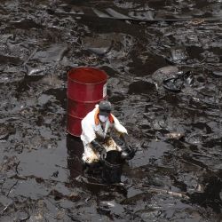 Un trabajador limpia el derrame de petróleo que se registró durante el proceso de descarga de crudo del buque Mare Dorium luego de un fuerte oleaje, en la playa de Ventanilla, en Callao, Perú. | Foto:Xinhua/Mariana Bazo