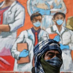 Un hombre mira mientras pasa junto a un mural basado en los protocolos de seguridad del coronavirus Covid-19 en las paredes de un paso subterráneo durante el toque de queda impuesto en Nueva Delhi para frenar la propagación del coronavirus Covid-19. | Foto:Sajjad Hussain / AFP