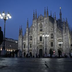 Una pareja cruza la Piazza Duomo pasando por la catedral, tras la puesta de sol en Milán, Italia. | Foto:PIERO CRUCIATTI / AFP