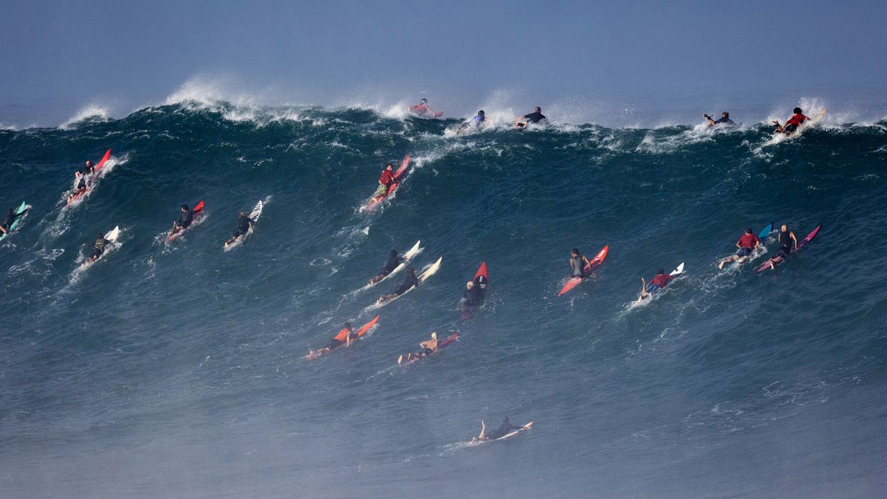 Surfistas remando para poder tomar olas en la bahía de Waimea, Hawái. - La bahía de Waimea, en la costa norte de Oahu, es famosa por sus olas de 9 metros. | Foto:Brian Bielmann / AFP
