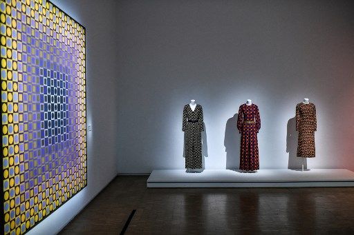 Tres Yves Saint Laurent de las colecciones 1968, 1969 y 1970, próximas a un cuadro de Victor Vasarely.