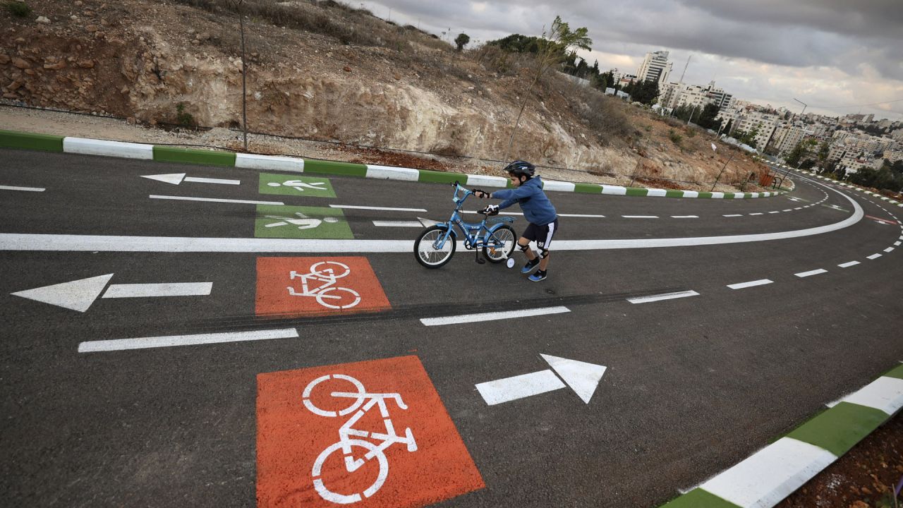 Un niño palestino empuja su bicicleta a lo largo de un sendero de uso mixto de 500 metros, con zonas dedicadas al deporte, en la ciudad palestina de Ramala, en la Cisjordania ocupada por Israel. - El proyecto creado por el Ayuntamiento de Ramallah es el primero de este tipo en los territorios palestinos. | Foto:ABBAS MOMANI / AFP