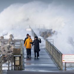La gente camina por un puente de madera en la costa del Mar del Norte en medio de espumas mientras las ráfagas de tormenta golpean Noerre Vorupoer en el norte de Jutlandia en Dinamarca. | Foto:Bo Amstrup / Ritzau Scanpix / AFP