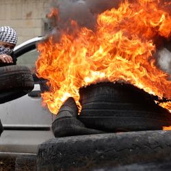 Un joven palestino quema neumáticos durante los enfrentamientos con las fuerzas de seguridad israelíes, tras una manifestación contra la expropiación de tierras por parte de Israel, en el pueblo de Kfar Qaddum, cerca del asentamiento judío de Kedumim, en la Cisjordania ocupada. | Foto:JAAFAR ASHTIYEH / AFP