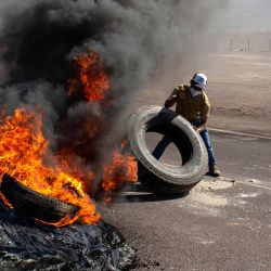 Un manifestante mueve un neumático mientras bloquea una ruta de acceso a Iquique, Chile, durante una huelga regional convocada por diferentes organizaciones contra la inmigración ilegal. | Foto:DIEGO REYES / AFP