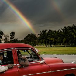 Un viejo coche estadounidense es visto en La Habana mientras un arco iris aparece en el cielo. | Foto:YAMIL LAGE / AFP