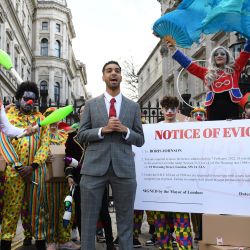 El influencer y youtuber británico Niko Omilana pronuncia un discurso mientras se encuentra entre personas disfrazadas durante una protesta escenificada frente a las puertas de Downing Street, en Londres, pidiendo la dimisión del primer ministro británico. | Foto:DANIEL LEAL / AFP