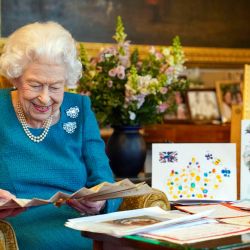 La imagen muestra a la reina Isabel II de Gran Bretaña mirando el abanico de autógrafos de la reina Victoria, junto a una muestra de recuerdos de sus Jubileos de Oro y Platino, en la Sala del Roble del Castillo de Windsor, al oeste de Londres. | Foto:Steve Parsons / POOL / AFP