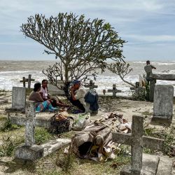 Familiares sentados junto a los cuerpos exhumados de las tumbas destruidas por el ciclón Batsirai en el cementerio local de Mahanoro, Madagascar. | Foto:Laure Verneau / AFP