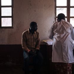 Dos técnicos de laboratorio del equipo de investigación científica del Dr. Tony Ukety examinan un trozo de carne que puede contener gusanos de la oncocercosis de las piernas de un hombre en la aldea de Kanga, provincia de Ituri, al noreste de la República Democrática del Congo. | Foto:ALEXIS HUGUET / AFP