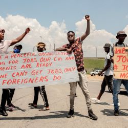 Los sudafricanos descontentos con la búsqueda de empleo sostienen pancartas mientras se manifiestan pidiendo que se limite el empleo de ciudadanos extranjeros en el país en Johannesburgo. | Foto:LUCA SOLA / AFP