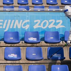 Un miembro del personal con equipo de protección personal (EPP) desinfecta las gradas después de la final de big air de esquí de estilo libre masculino durante los Juegos Olímpicos de Invierno de Pekín 2022 en el Big Air Shougang en Pekín. | Foto:SEBASTIEN BOZON / AFP