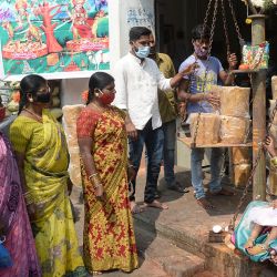 Una devota hindú junto con su hija se sienta en una balanza para comprar jaggery en una cantidad igual a su peso para adorar a las deidades tribales antes del festival Medaram Jatara, en una tienda mayorista en Hyderabad, India. | Foto:NOAH SEELAM / AFP