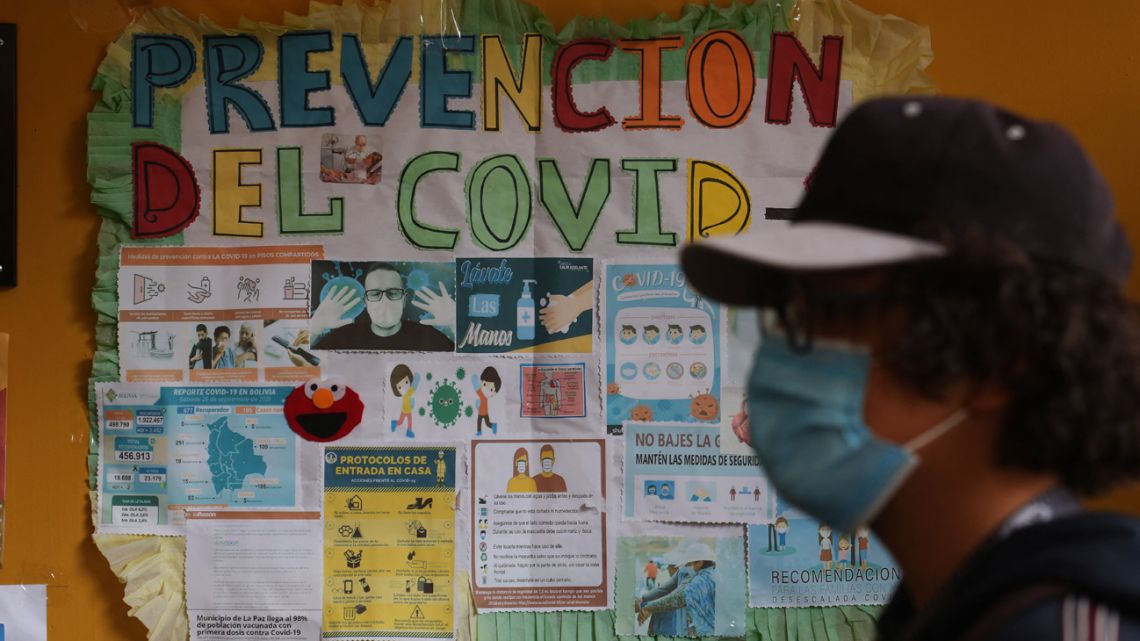 A person walks past a poster giving instructions on how to prevent Covid-19 as face-to-face classes resume after vacations at the Antonio Díaz Villamil education unit in La Paz on February 1, 2022.