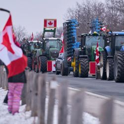 Un niño sostiene una bandera nacional canadiense en el lugar del bloqueo de la autopista 402 por parte de los agricultores en protesta por los mandatos de vacunación, cerca de Sarnia, Ontario, Canadá. | Foto:Geoff Robins / AFP