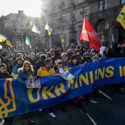 Manifestantes gritan eslóganes mientras marchan detrás de una pancarta en la que se lee "Los ucranianos resistirán" con los colores de la bandera nacional durante una concentración en Kiev, celebrada para mostrar la unidad en medio de las advertencias de Estados Unidos sobre una inminente invasión rusa. | Foto:SERGEI SUPINSKY / AFP