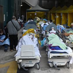 Personas acostadas en camas de hospital en el exterior del Centro Médico de Cáritas en Hong Kong, mientras la ciudad se enfrenta a su peor ola de coronavirus Covid-19 hasta la fecha. | Foto:PETER PARKS / AFP
