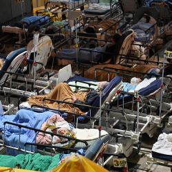 Personas acostadas en camas de hospital con la temperatura cayendo por la noche fuera del Centro Médico de Caritas en Hong Kong, mientras los hospitales se ven desbordados con la ciudad enfrentándose a su peor ola de coronavirus Covid-19 hasta la fecha. | Foto:PETER PARKS / AFP