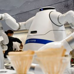 Un empleado sirve café mientras un robot prepara una jarra fresca en una zona de espera dentro de la "burbuja" de circuito cerrado en la estación de tren de Taizicheng -creada como medida preventiva contra el coronavirus Covid-19- en Zhangjakou antes de los Juegos Olímpicos de Invierno de Pekín 2022. | Foto:Jewel Samad / AFP