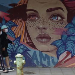Una pareja camina frente a un grafiti, en Brasilia, Brasil. | Foto:Xinhua/Lucio Tavora