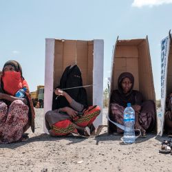 Mujeres sentadas bajo cajas de cartón marcadas por el Alto Comisionado de las Naciones Unidas para los Refugiados mientras esperan ser registradas por las autoridades en el complejo del Hotel Agda, en la ciudad de Semera, región de Afar, Etiopía. | Foto:EDUARDO SOTERAS / AFP