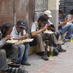 Personas consumen alimentos entregados por voluntarios, en el centro de Lima, Perú. | Foto:Xinhua/Mariana Bazo