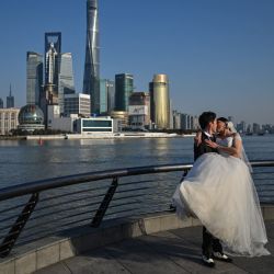 Una pareja posa para un fotógrafo de bodas en el paseo del Bund a lo largo del río Huangpu en Shanghai. | Foto:HECTOR RETAMAL / AFP