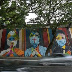 Vista de la obra "Coexistencia" del artista brasileño Eduardo Kobra -que muestra a niños con máscaras faciales a causa del nuevo coronavirus, COVID-19, con símbolos de diferentes religiones en Sao Paulo, Brasil. | Foto:NELSON ALMEIDA / AFP