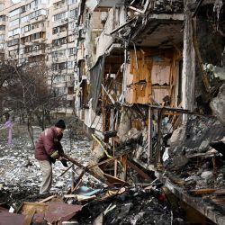 Un hombre limpia los escombros de un edificio residencial dañado en la calle Koshytsa, un suburbio de la capital ucraniana, Kiev, donde cayó un misil militar ruso. | Foto:DANIEL LEAL / AFP