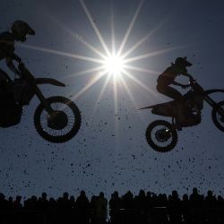 Los pilotos se ven contra el sol mientras toman un salto durante la primera carrera de la clase MX2 durante el MXGP de motocross de Gran Bretaña en Matterley Basin en Winchester, sur de Inglaterra. | Foto:ADRIAN DENNIS / AFP