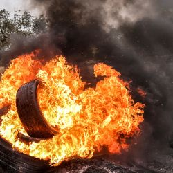 Manifestantes palestinos queman neumáticos durante los enfrentamientos con las fuerzas de seguridad israelíes tras una manifestación contra los asentamientos en el pueblo de Beita, en la Cisjordania ocupada. | Foto:RONALDO SCHEMIDT / AFP