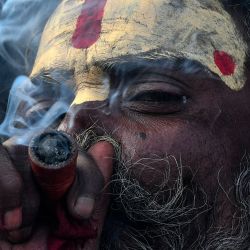Un sadhu o santón hindú fuma marihuana utilizando un "chillum", una pipa de arcilla tradicional, como ofrenda sagrada con motivo del festival Maha Shivaratri en la zona del templo de Pashupatinath en Katmandú, Nepal. | Foto:PRAKASH MATHEMA / AFP
