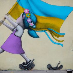 Un transeúnte pasa junto a un fresco del artista callejero Seth que representa a una niña con una bandera ucraniana caminando sobre tanques en París. | Foto:JOEL SAGET / AFP